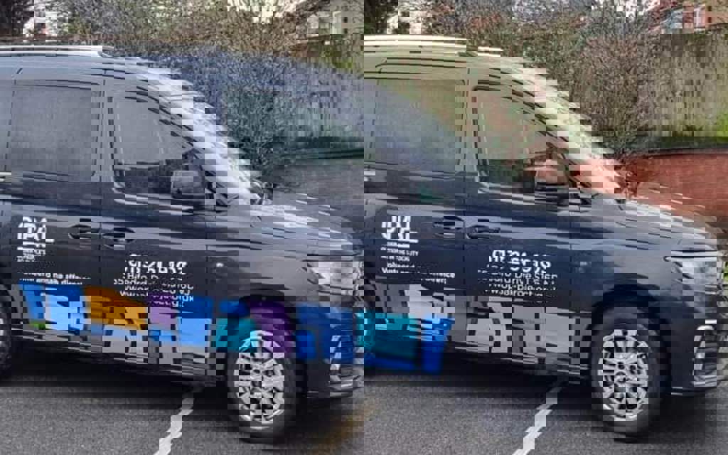 An image of OPAL's wheelchair accessible vehicle. The vehicle is black and has their logo and telephone number on the side.