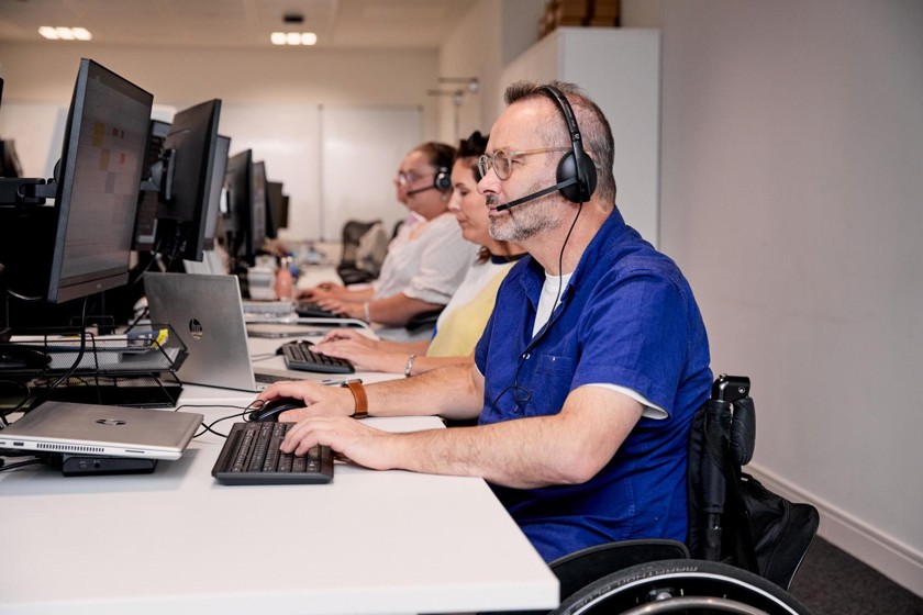 A gentleman is at a desk with a headset on working on his computer.