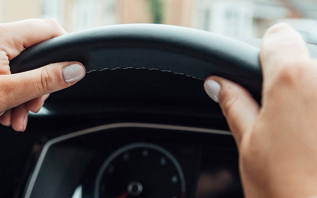 Person with their hands on a steering wheel. 