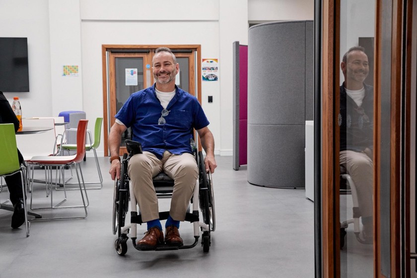 A man in a wheelchair is moving through an office.